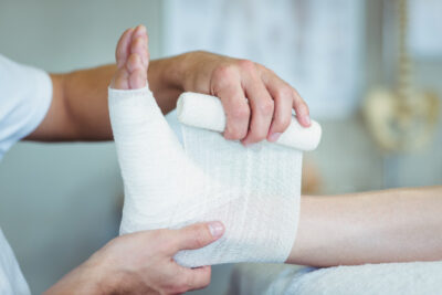 physiotherapist-putting-bandage-injured-feet-patient_107420-58409